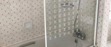 Ducha con cerramiento de vidrio, un cabezal de ducha de mano y un cabezal de ducha fijo.