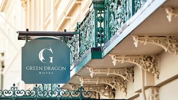 Ein Hotelschild mit dem Namen "GREEN DRAGON HOTEL" und verzierten Balkonläufen.
