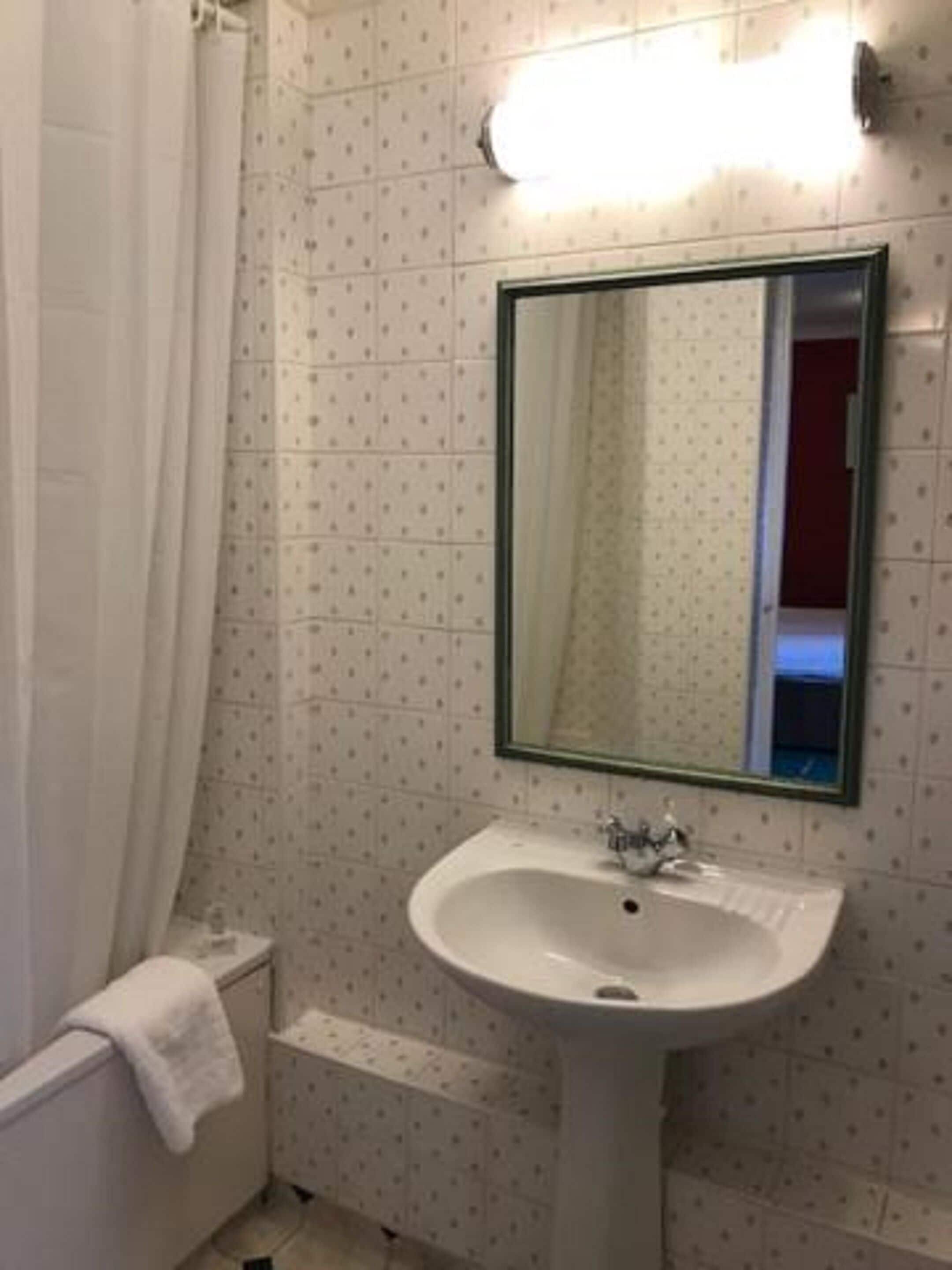 A bathroom with a white sink, a mirror, and a shower curtain.