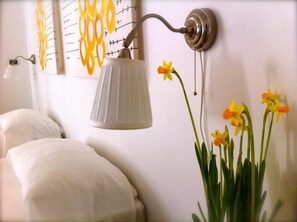 A bedroom with a bed, a wall-mounted lamp, and a vase with flowers. - La torre e il mare (Monopoli)