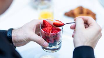 Une personne tenant un verre contenant des fraises et une cuillère.