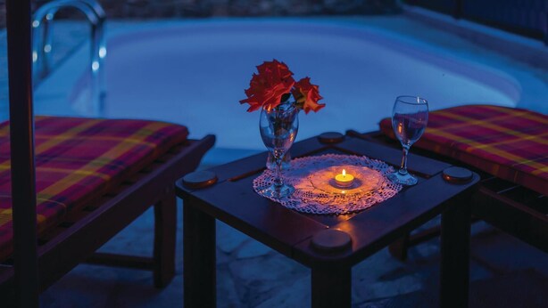 A poolside table with a candle, a glass, and a vase with red flowers. - Beautiful home in Oklaj (Oklaj)