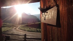 A rustic wooden barn with a view of a mountain road and a sunset. - Ferienwohnung Hochkalter, 1-2 Erwachsene + 1 Kind, 40 qm, Dusche/WC, TV, W-LAN, Ostbalkon, 1 Schlafzimmer, Nichtraucher (Ramsau bei Berchtesgaden)