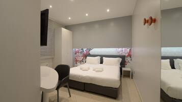 Un dormitorio moderno con una cama grande, una mesita de noche, una silla y una pequeña mesa.