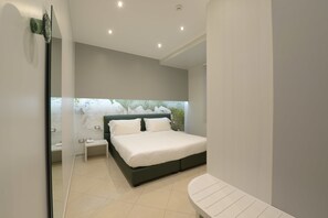 A modern bedroom with a bed, bedside tables, and a view of greenery through a window. - Imperiali Hotel (Francavilla Fontana)