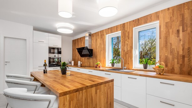 Een moderne keuken met witte kasten, een houten eiland en een inbouwoven.