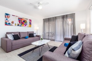 Ein modernes Wohnzimmer mit grauem Sofa, einem weißen Couchtisch und einem großen abstrakten Gemälde an der Wand.