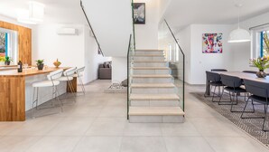 Een moderne keuken met een houten keukeneiland, barstoelen en een trap naar een hoger niveau.