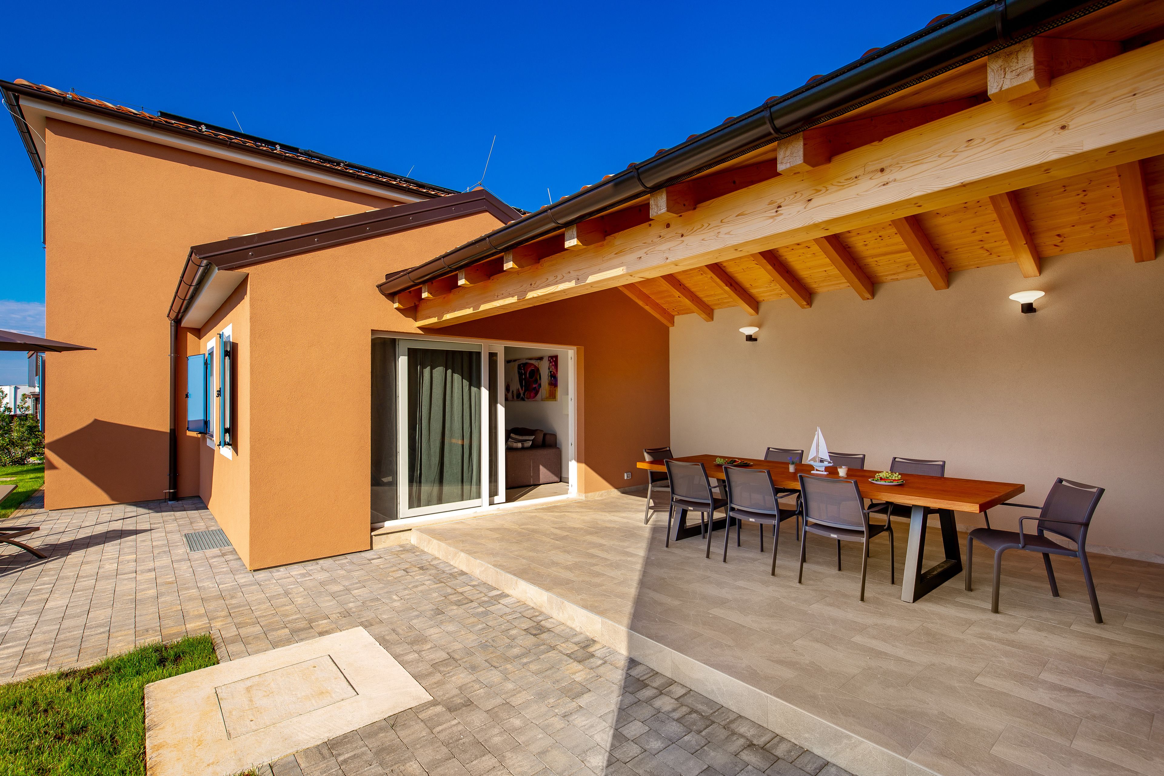 Un patio cubierto con mesa y sillas, una puerta corrediza de vidrio y piso de baldosas.
