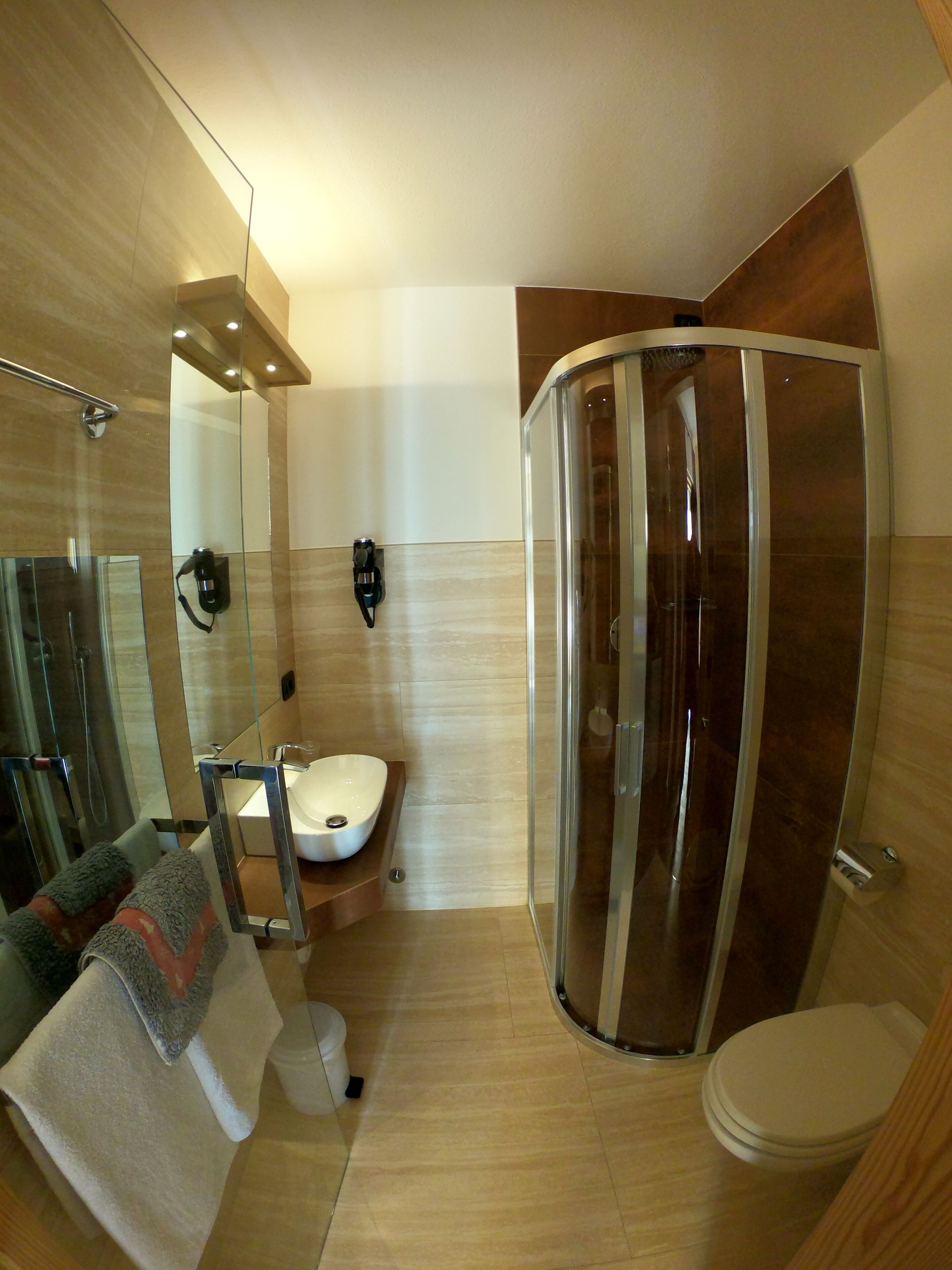 Ein modernes Badezimmer mit Duschkabine aus Glas, einem freistehenden Waschbecken und einer Toilette.