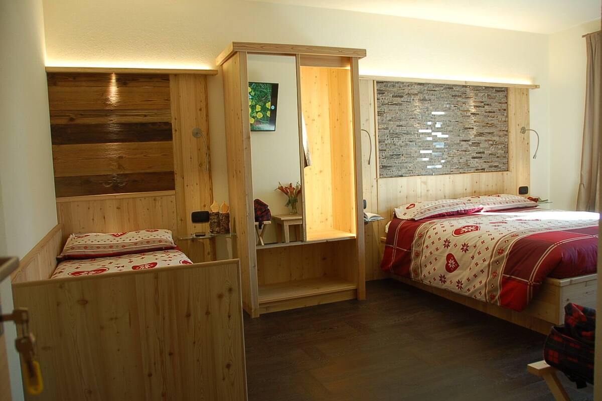 Ein kleines Zimmer mit zwei Holzbetten, einem kleinen Tisch und einem Spiegel.