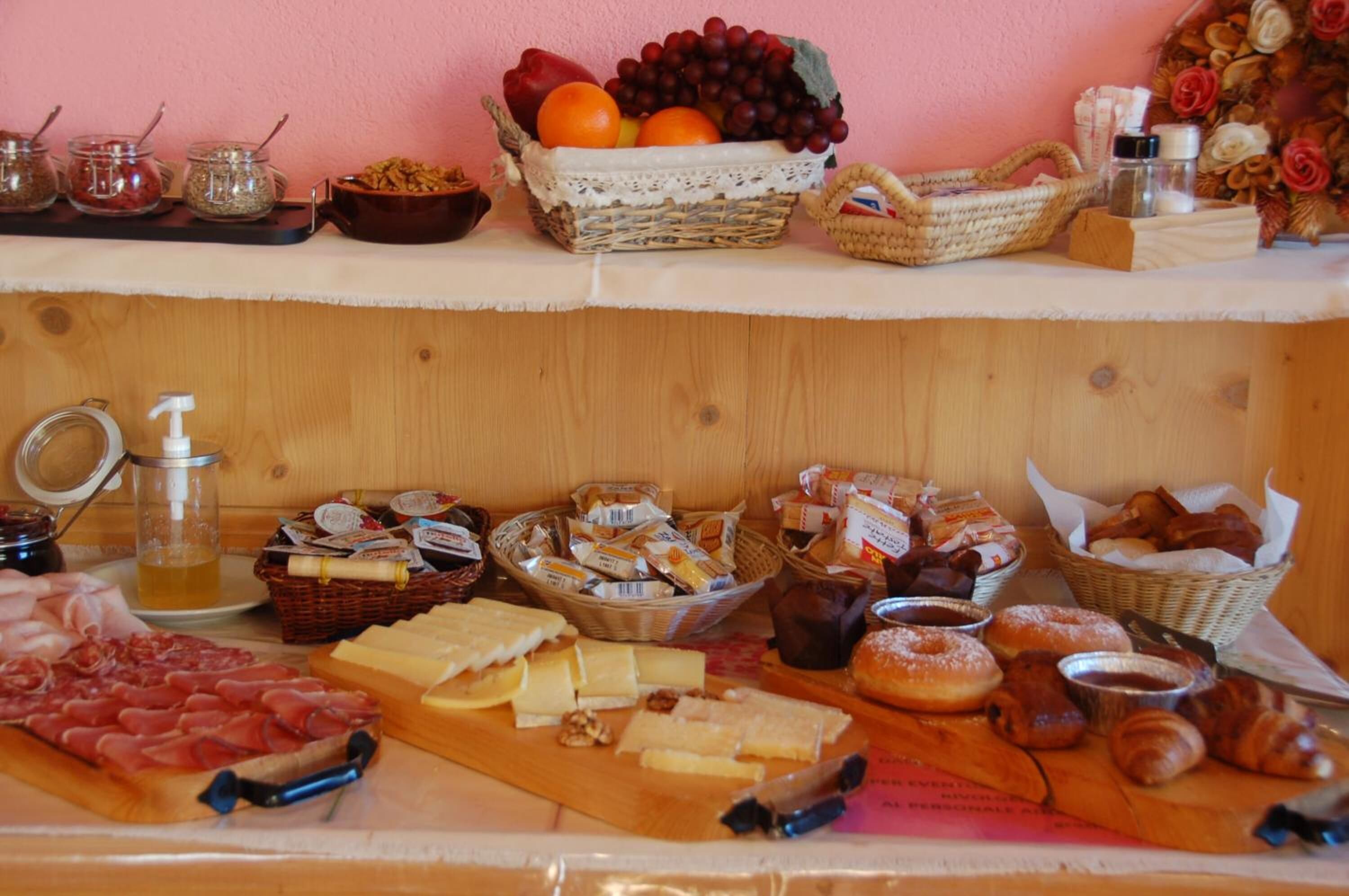 Una mesa de buffet con diversos alimentos, incluyendo carnes, quesos, pasteles y frutas.