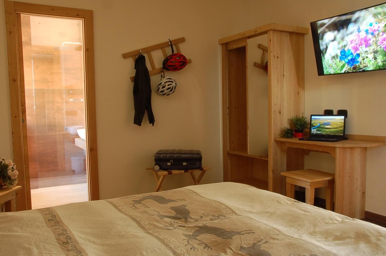 Un dormitorio con una cama, un escritorio de madera, un televisor y una maleta.