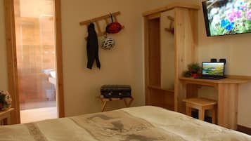 Un dormitorio con una cama, un escritorio de madera, un televisor y una maleta.