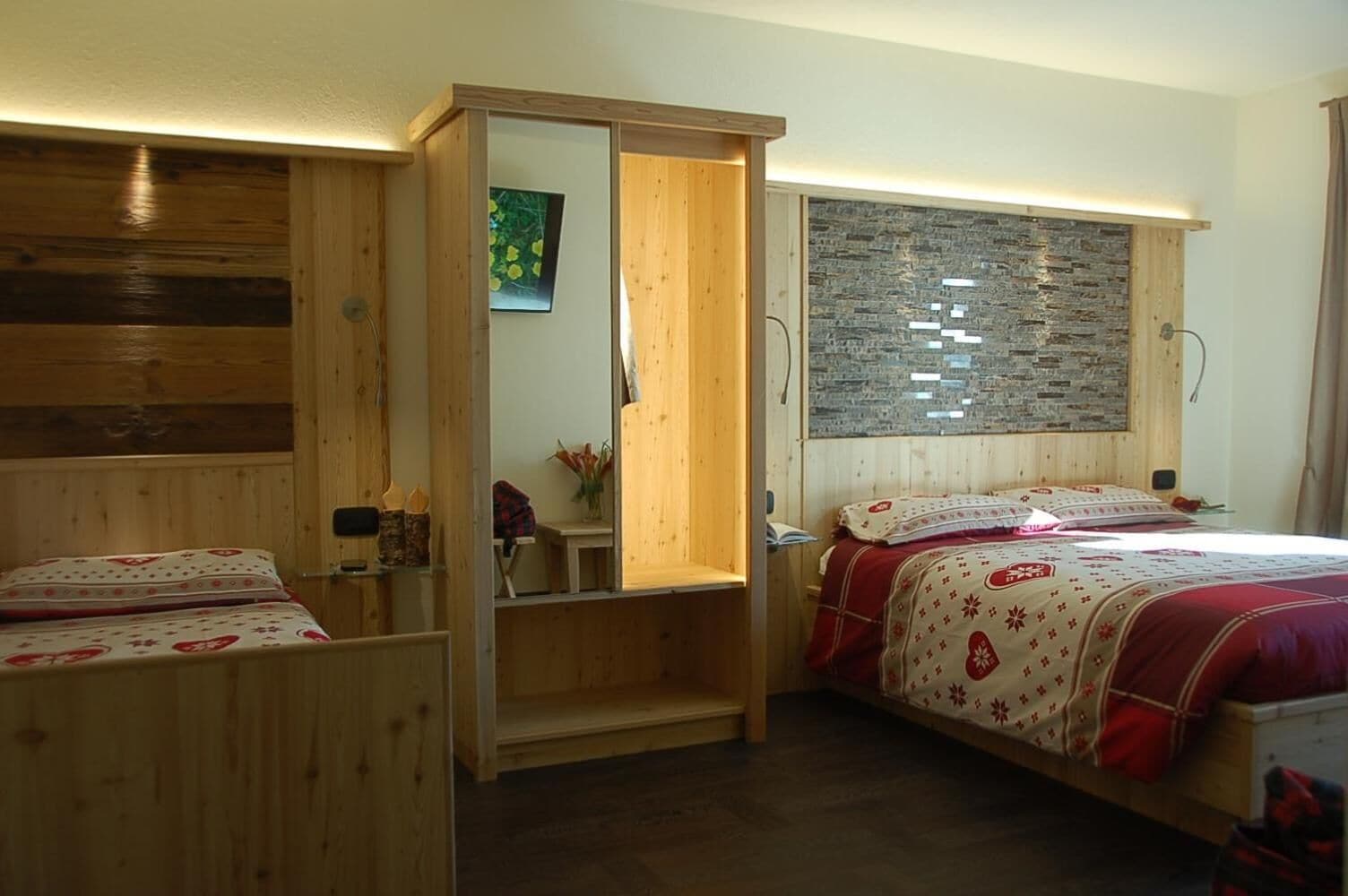 A bedroom with two beds, wooden walls, a stone wall, and a small shelf with a vase.