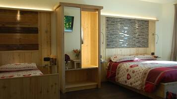 A bedroom with two beds, wooden walls, a stone wall, and a small shelf with a vase.