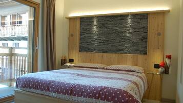 A bedroom with a bed, wooden headboard, and a stone accent wall.