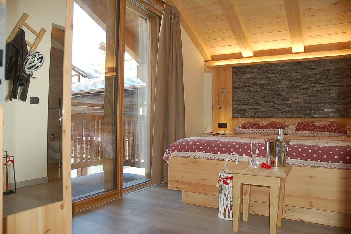 Ein Schlafzimmer aus Holz mit einem großen Bett, einem Holzbüro und einer Schiebetür zu einem Außenbereich.