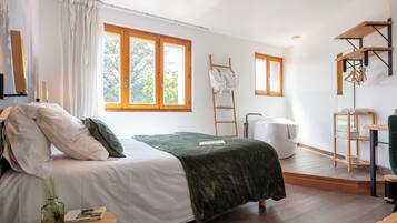 Een moderne slaapkamer met een bed, een groene plaid, een nachtkastje met een boek en brillen, een houten ladder en een witte stoel.