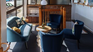 Una habitación acogedora con un sofá azul, un sillón azul y una pequeña mesa redonda con una lámpara.