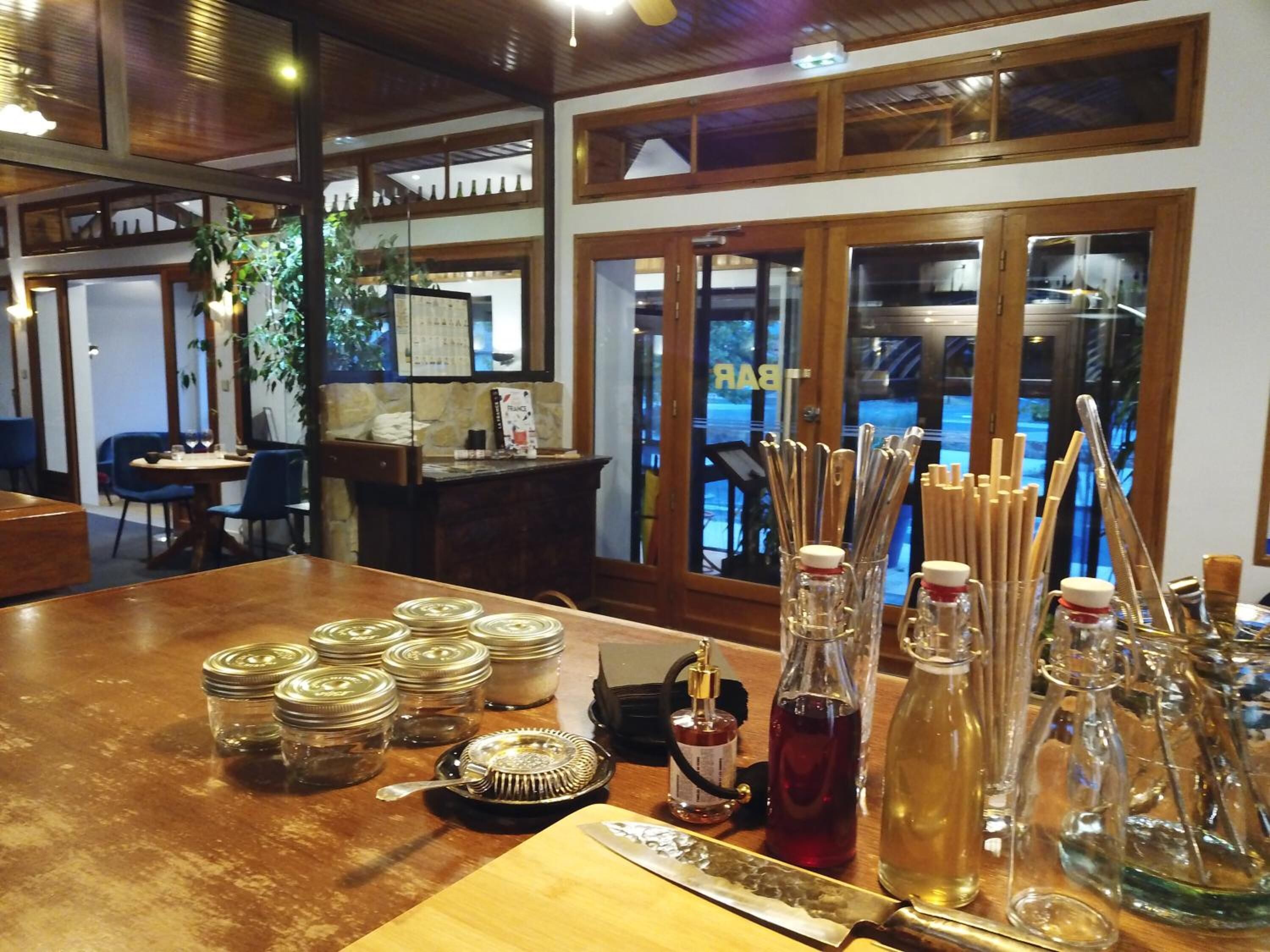 L’intérieur d’un restaurant, avec des tables et des chaises en bois, ainsi qu’une variété de verres et d’ustensiles disposés sur les tables.