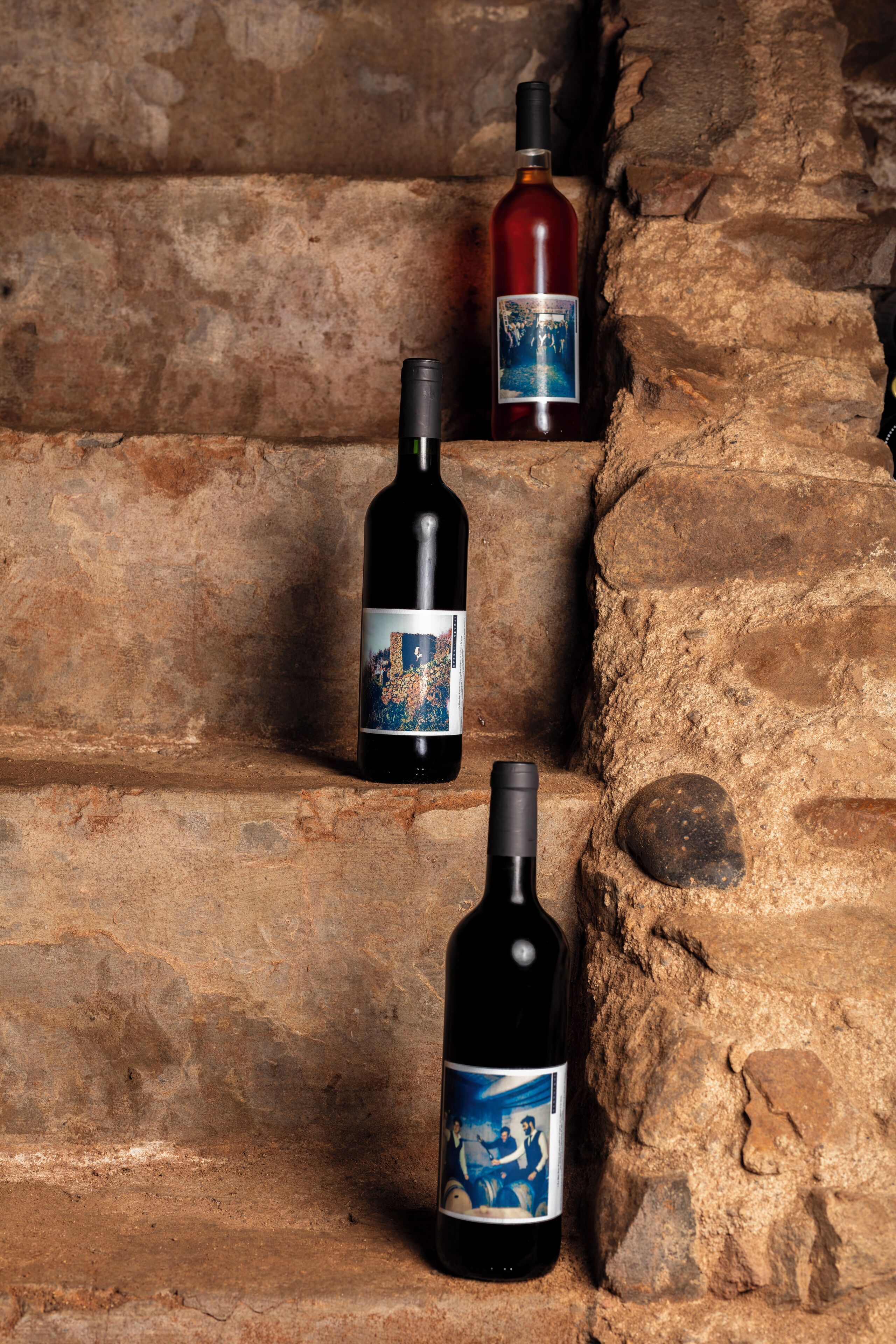 Tres botellas de vino sobre peldaños de piedra.