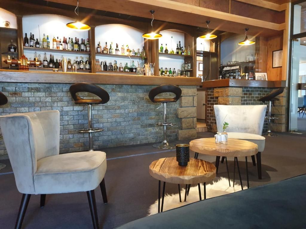 A bar area with a stone wall, bar stools, and a round wooden table with a mug.