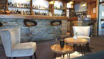 A bar area with a stone wall, bar stools, and a round wooden table with a mug.