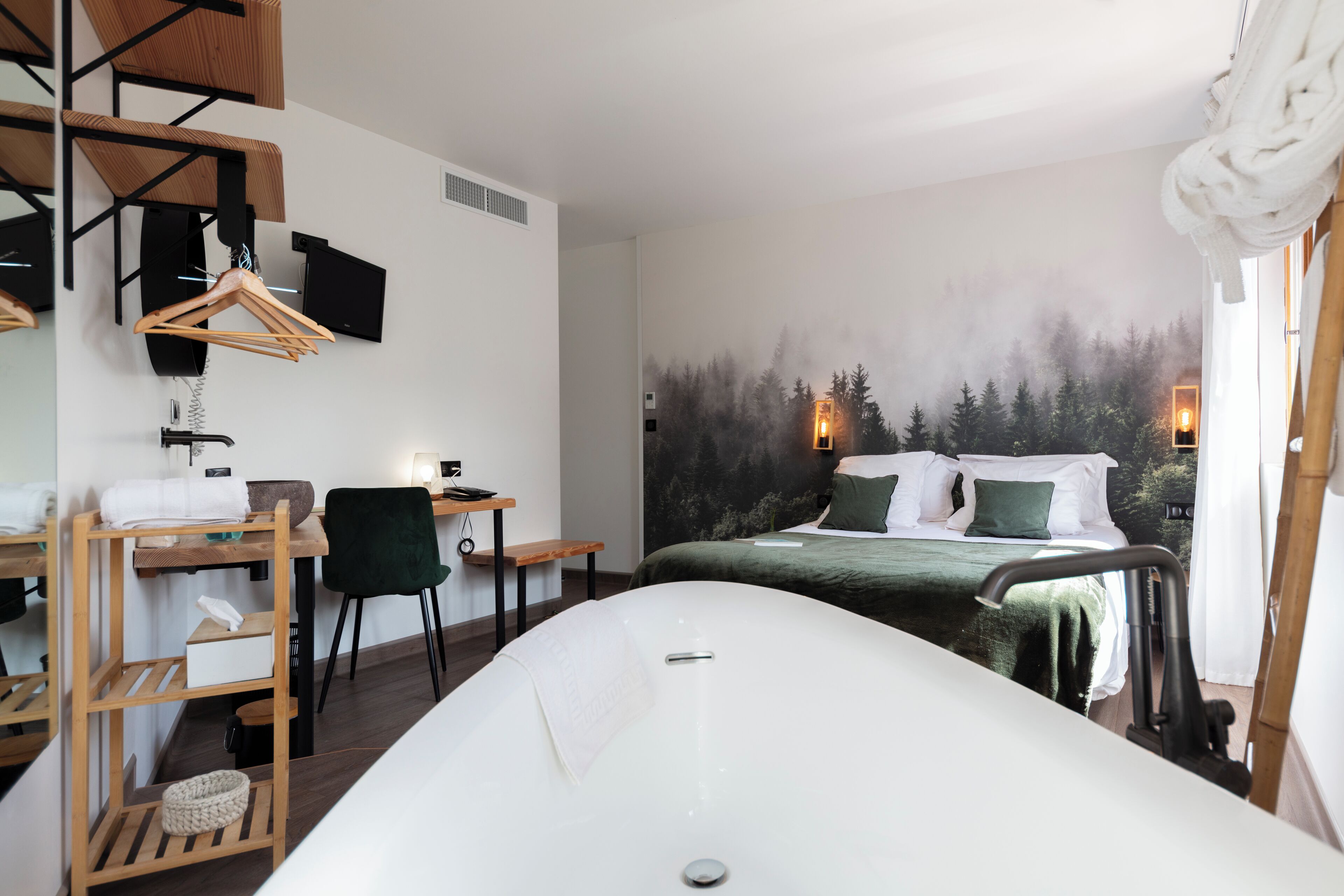 Un dormitorio moderno con una cama grande, un escritorio, una silla y una bañera.