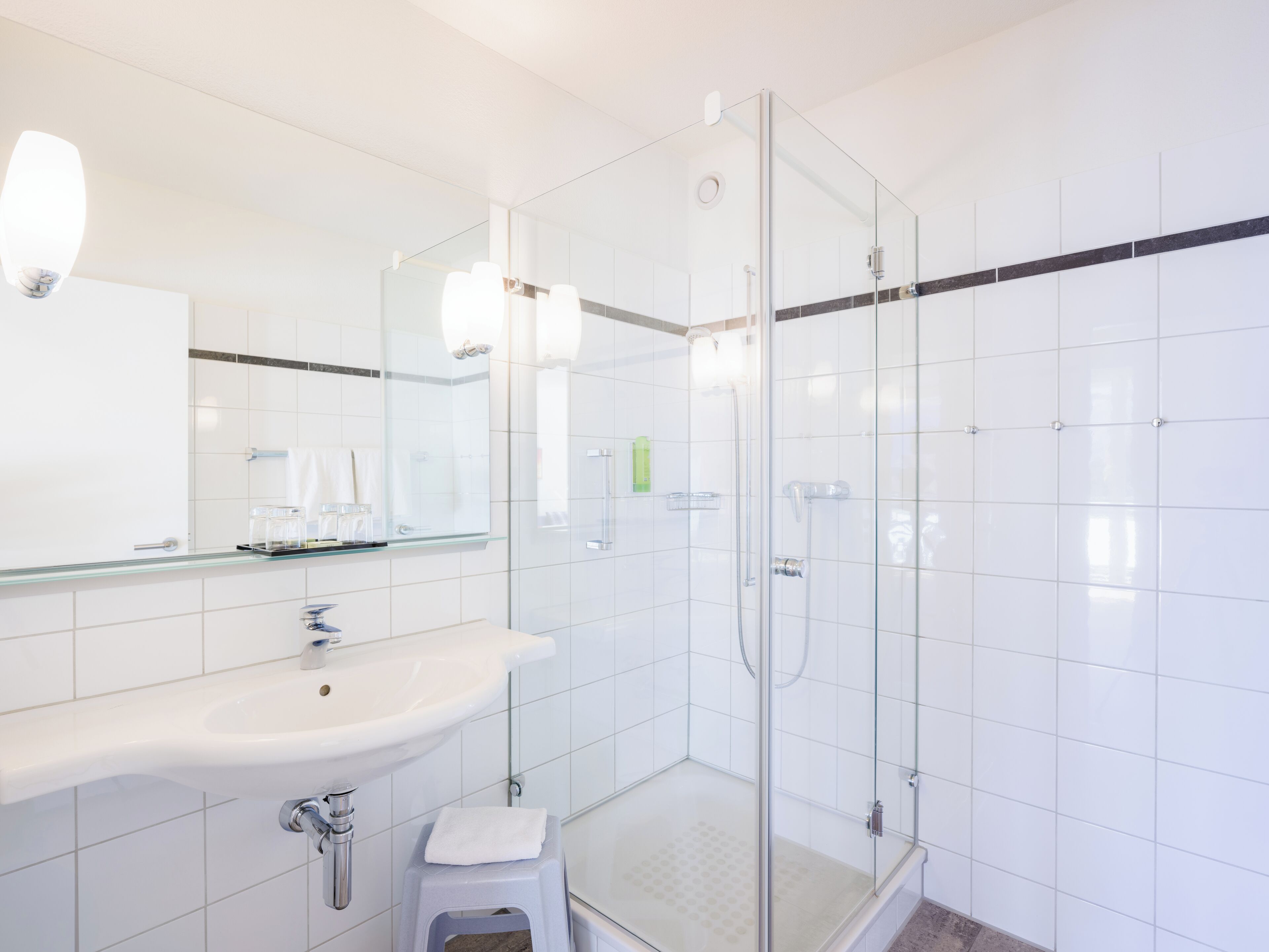 A modern bathroom with a glass shower enclosure, a white sink, and a large mirror.