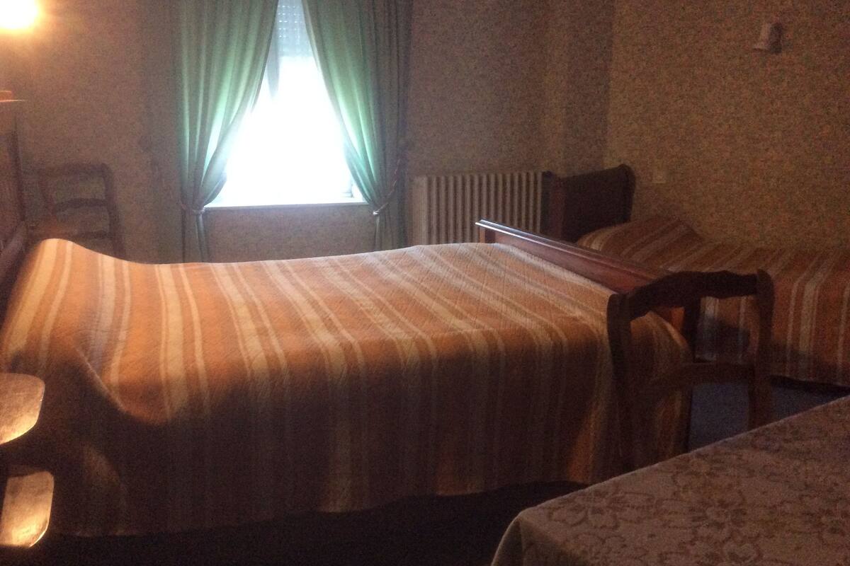Une chambre d’hôtel avec un lit, une chaise, une table et une fenêtre avec des rideaux.