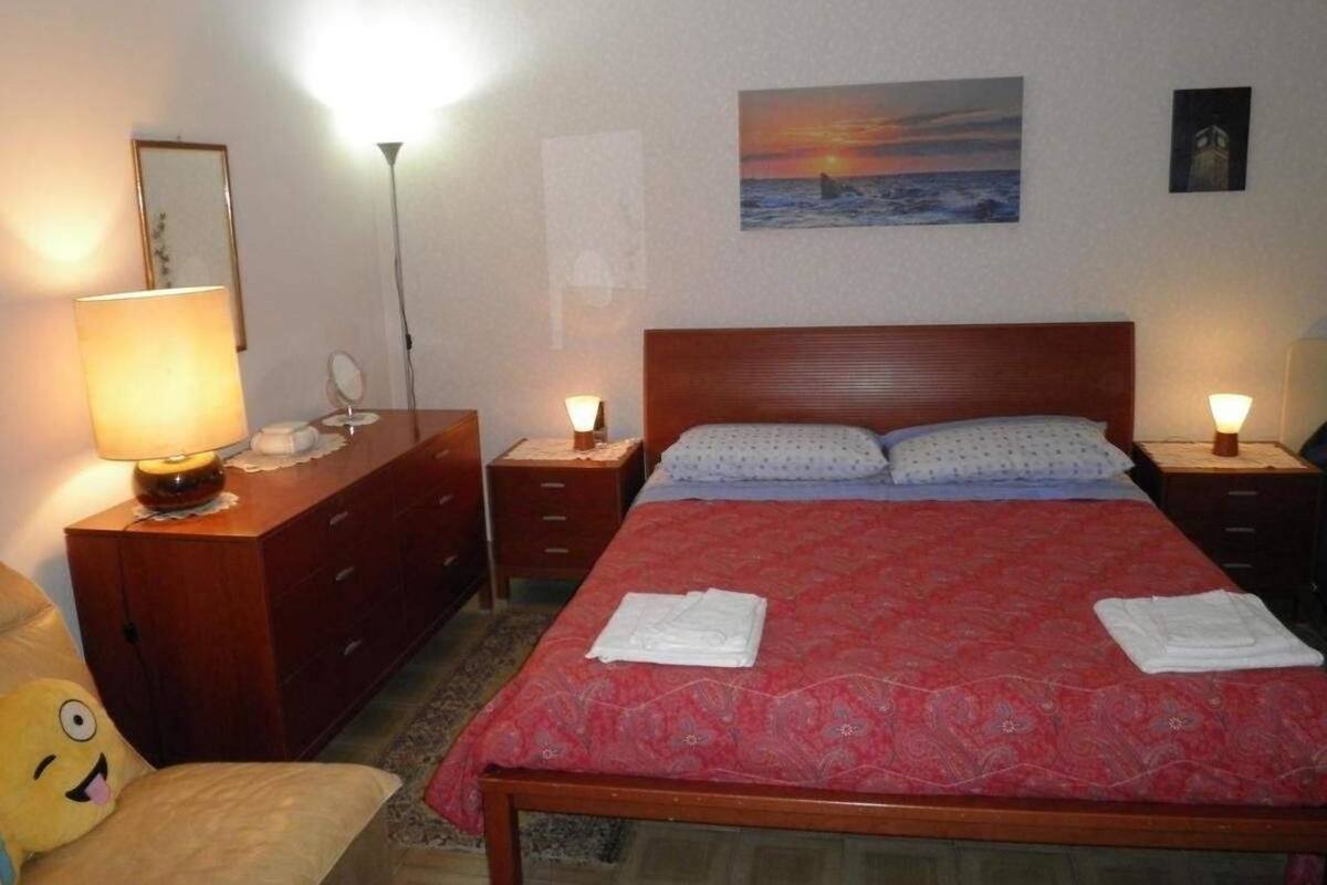 A neatly arranged bedroom with a large bed, two bedside tables with lamps, a wooden dresser, and a wall-mounted painting.