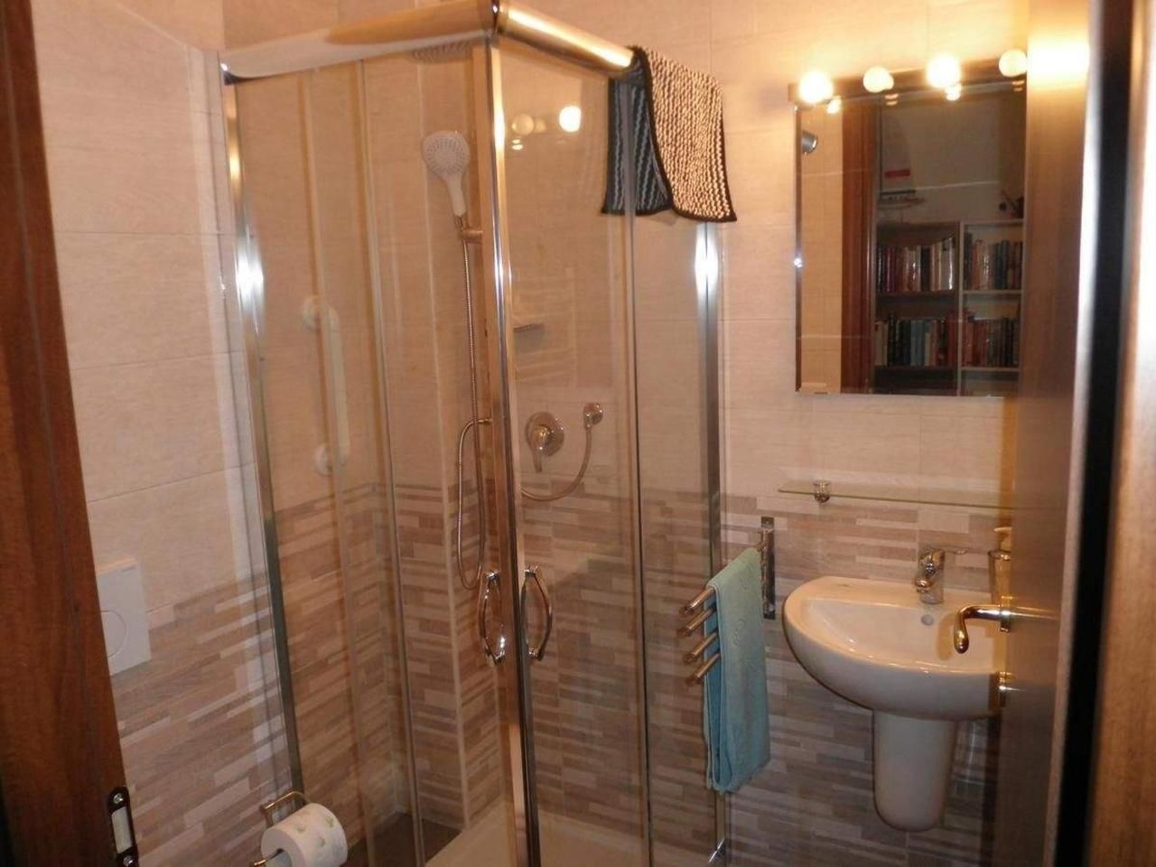 Eine Duschkabine mit Handtuchhalter und Waschbecken mit Spiegel darüber.