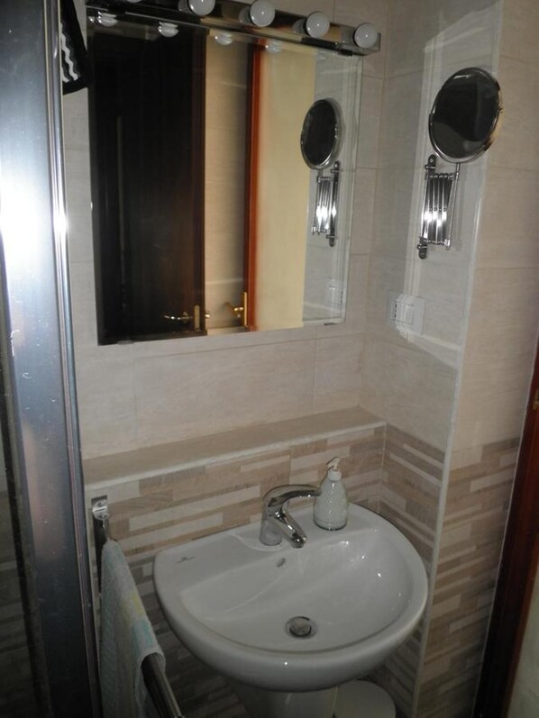 Un baño con lavamanos, espejo y ducha.