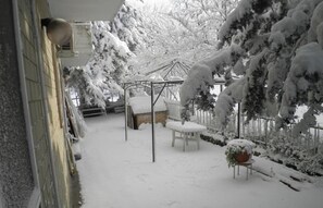 A snow-covered patio area with a gazebo, a white chair, and a table. - Don Milani (Matera)
