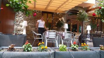 An outdoor patio area with metal chairs and tables, stone walls, and potted plants.