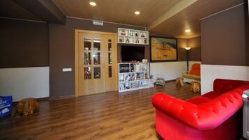 A room with a red sofa, wooden flooring, a bookshelf, and a door with glass panels.