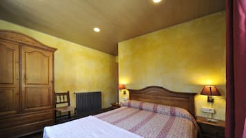 Un dormitorio con un armario de madera, una cama con colcha estampada, dos lámparas de noche y un radiador.