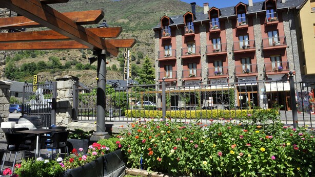 A hotel with multiple balconies, outdoor seating, and a mountain backdrop. - Hotel Vall d'Aneu (Esterri D'Aneu)