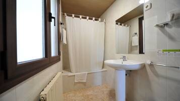 Een badkamer met raam, douchegordijn, wastafel en toilet.