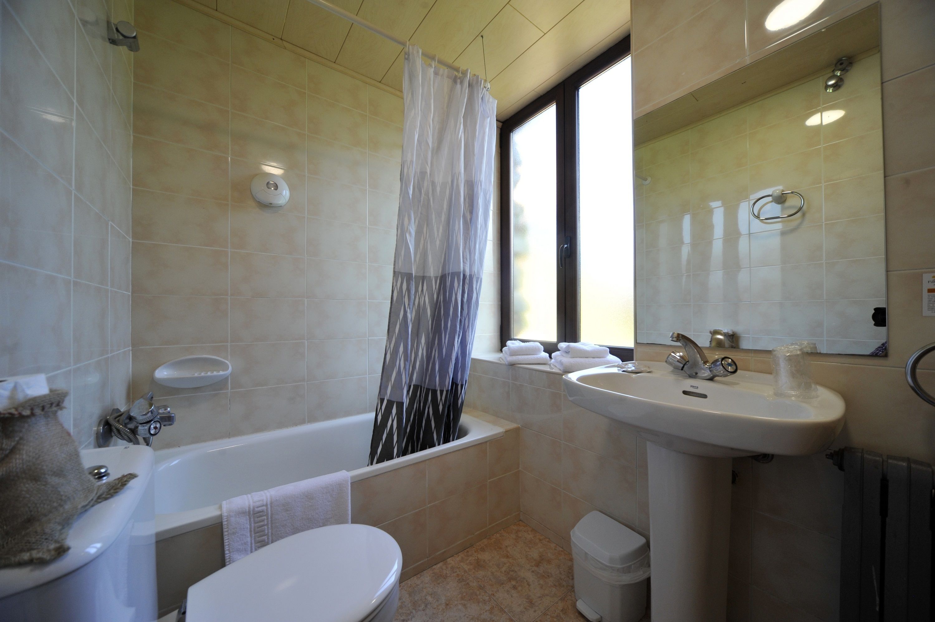 Ein Badezimmer mit Badewanne, Toilette, Waschbecken und einem Fenster mit Blick.