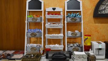 Una exhibición de productos para el hogar y jardín, que incluye flores, utensilios de cocina y una máquina de café.
