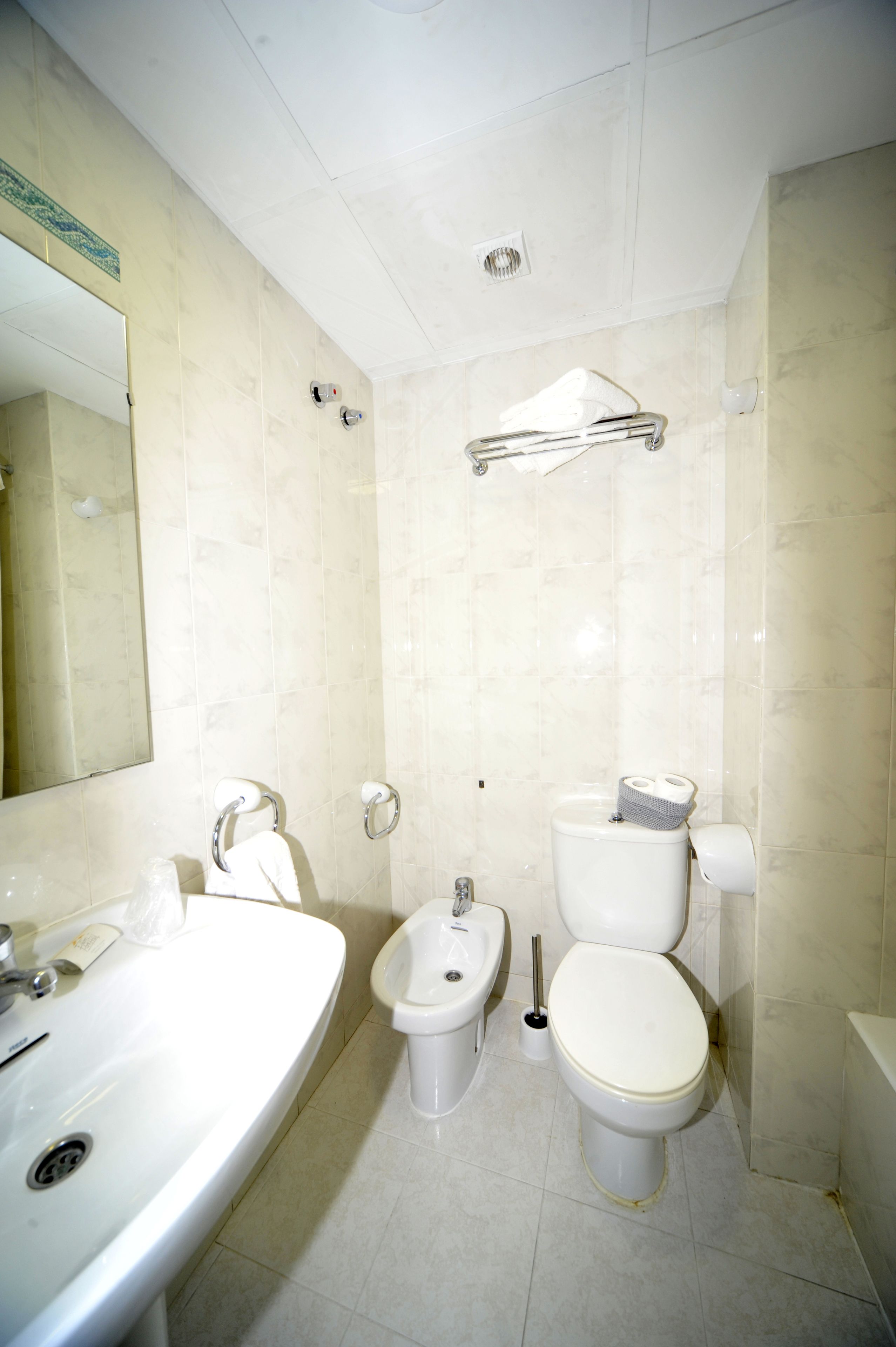 A bathroom with a sink, bidet, toilet, and a mirror.