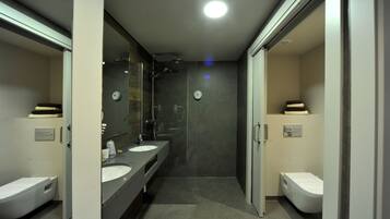 Une salle de bain moderne avec deux lavabos, une douche et des toilettes.