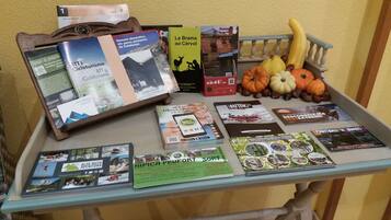 Una mesa con folletos, un libro y calabazas decorativas.