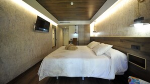 A modern hotel room with a large bed, wooden ceiling, and built-in TV. - Hotel Vall d'Aneu (Esterri D'Aneu)
