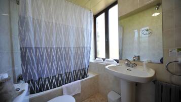 Ein Badezimmer mit Badewanne, Toilette, Waschbecken und einem Fenster mit Vorhang.