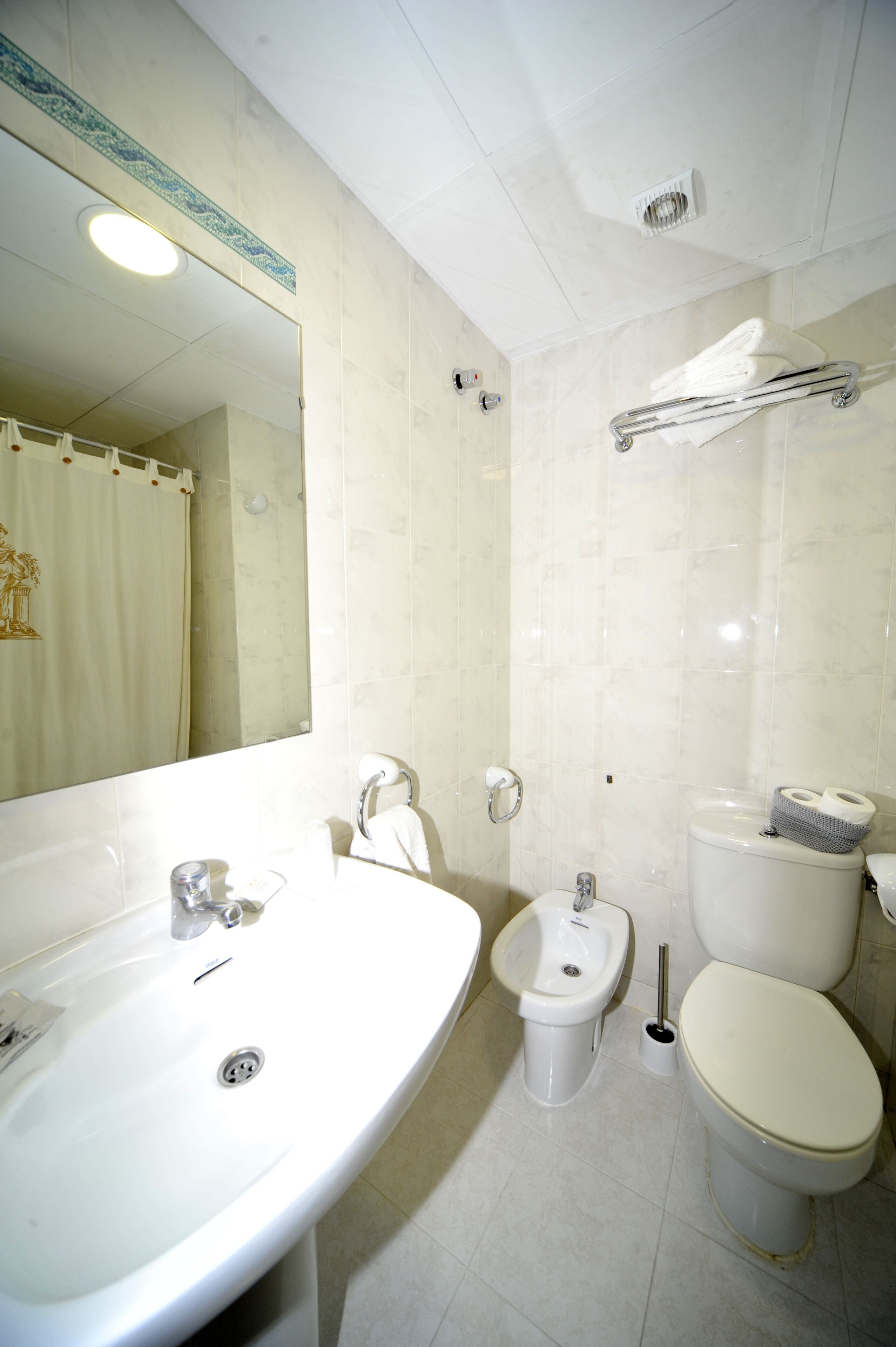 Un baño con lavamanos, bidé, inodoro y espejo.