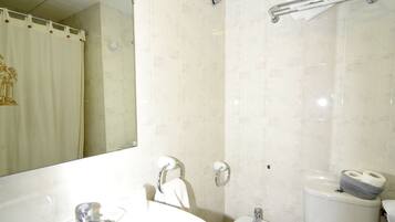 Un baño con lavamanos, bidé, inodoro y espejo.