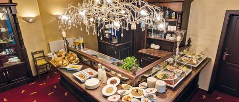 A buffet setup with various food items and a decorative chandelier.